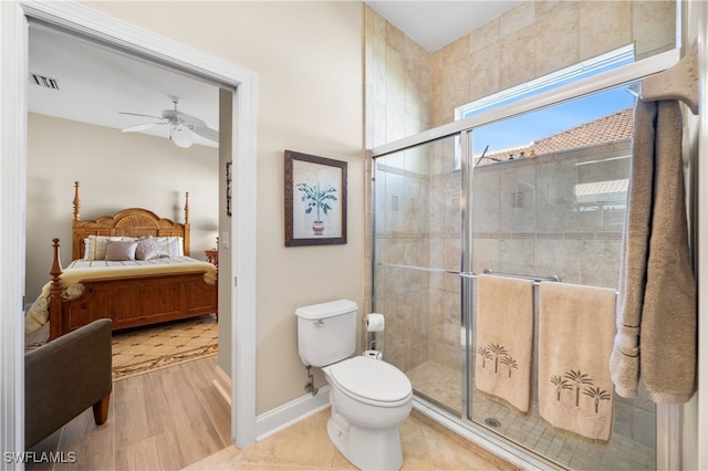 bathroom featuring ceiling fan, tile patterned flooring, a shower with shower door, and toilet