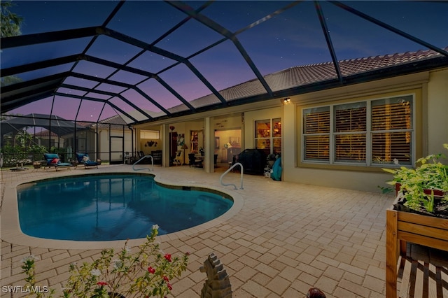 pool at dusk with a patio area and glass enclosure