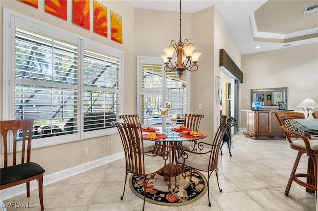 tiled dining area featuring a chandelier, a tray ceiling, plenty of natural light, and ornamental molding