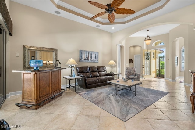 tiled living room featuring a tray ceiling, crown molding, and ceiling fan