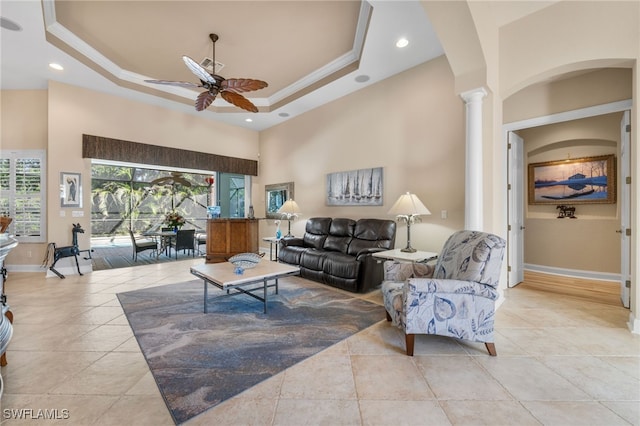 tiled living room with ceiling fan, a raised ceiling, ornamental molding, and ornate columns