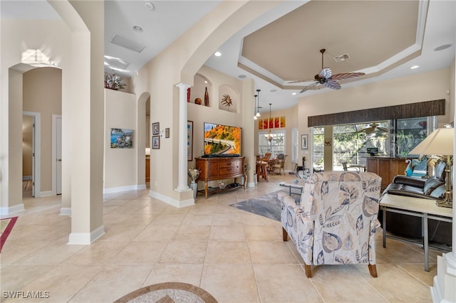 living room featuring light tile patterned floors, a tray ceiling, ceiling fan, and ornamental molding