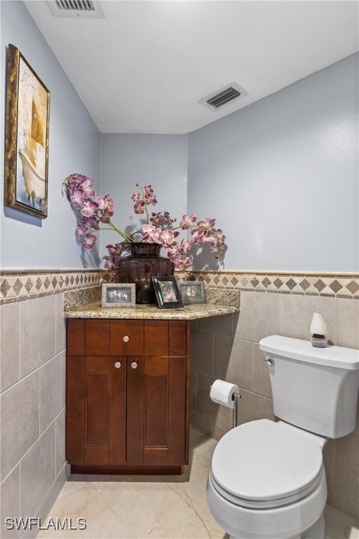 bathroom featuring tile walls, tile patterned flooring, and toilet