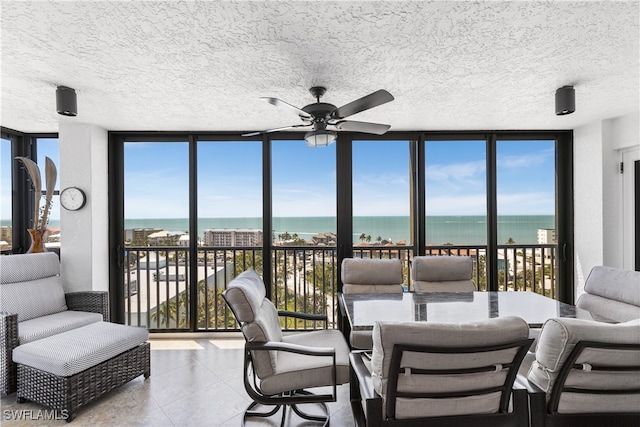 sunroom featuring a water view, ceiling fan, and plenty of natural light