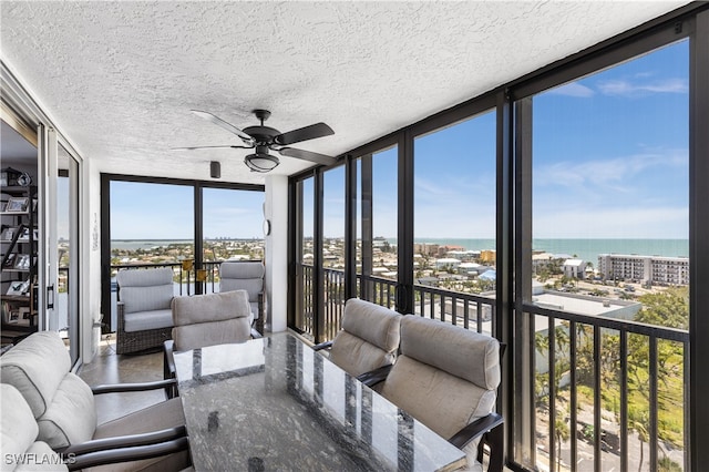 sunroom with a water view and ceiling fan