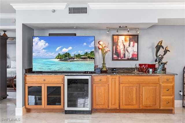 bar featuring dark stone countertops, beverage cooler, and crown molding