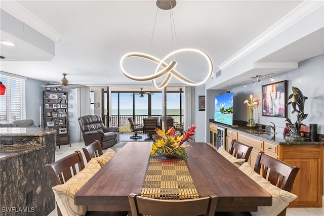 dining space with a wealth of natural light, ceiling fan with notable chandelier, beverage cooler, and ornamental molding