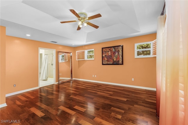 unfurnished bedroom featuring dark wood-type flooring, a raised ceiling, ceiling fan, and ensuite bathroom