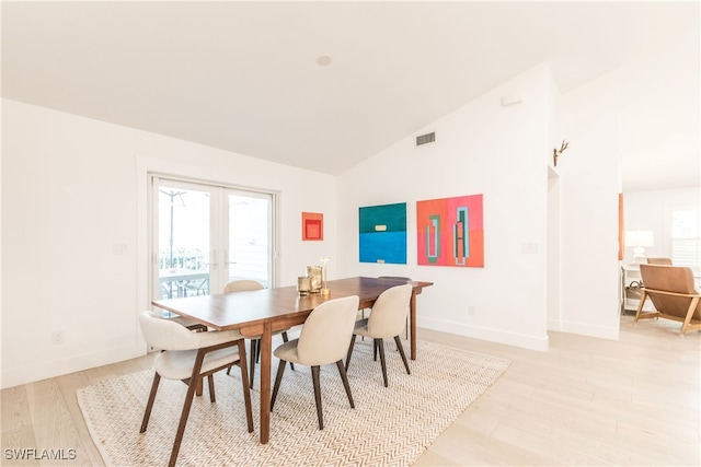 dining room featuring french doors, lofted ceiling, and light hardwood / wood-style flooring