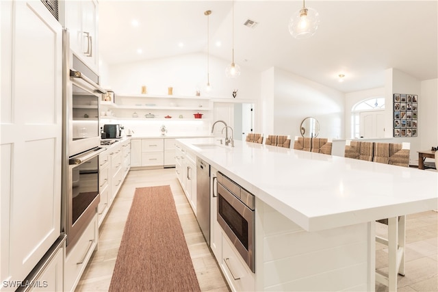 kitchen with decorative light fixtures, a large island with sink, a kitchen bar, and stainless steel appliances