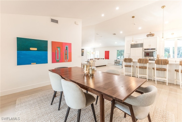 dining room featuring vaulted ceiling and light hardwood / wood-style flooring