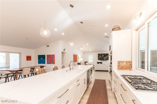 kitchen featuring vaulted ceiling, appliances with stainless steel finishes, decorative light fixtures, and sink