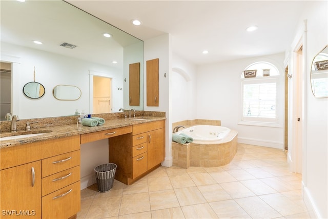 bathroom with tile patterned flooring, tiled tub, and vanity