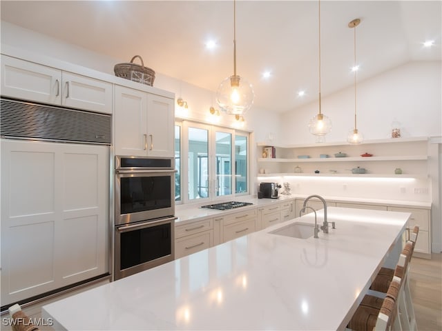 kitchen featuring white cabinets, lofted ceiling, decorative light fixtures, stainless steel appliances, and sink