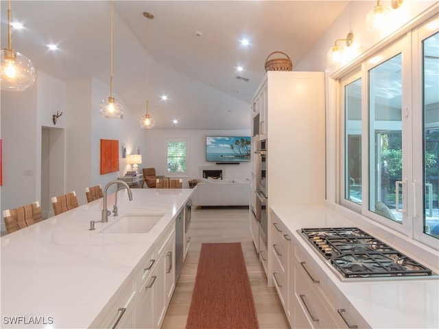 kitchen with stainless steel gas stovetop, white cabinets, and light stone counters