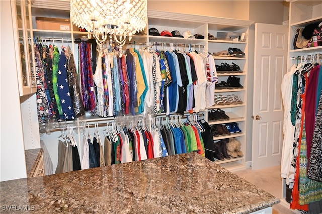 walk in closet featuring light carpet and a chandelier