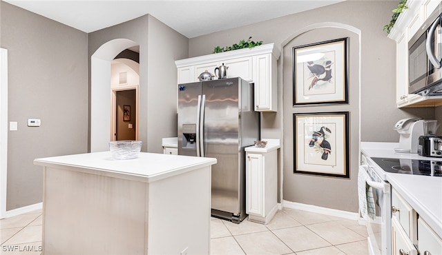 kitchen featuring white cabinetry, appliances with stainless steel finishes, light tile patterned floors, and a center island