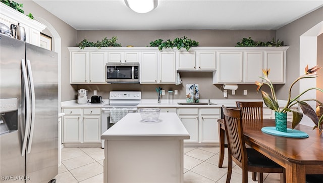 kitchen featuring a center island, white cabinets, light tile patterned floors, and stainless steel appliances