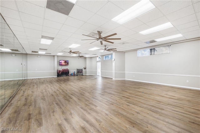 basement featuring light wood-type flooring, a drop ceiling, and ceiling fan