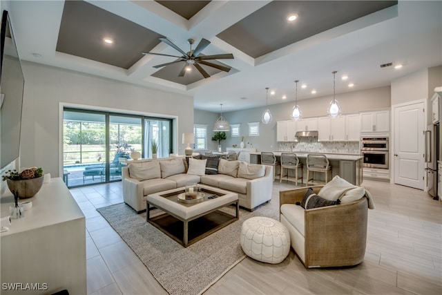 living room with beam ceiling, coffered ceiling, and ceiling fan