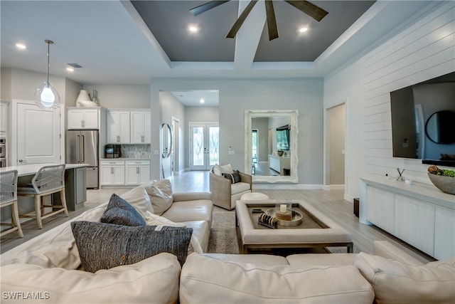 living room featuring french doors, ceiling fan, a tray ceiling, and light hardwood / wood-style floors