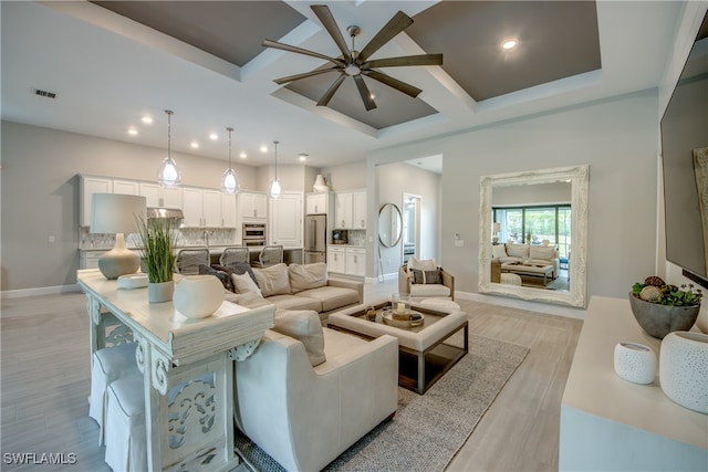 living room featuring coffered ceiling, light wood-type flooring, and ceiling fan