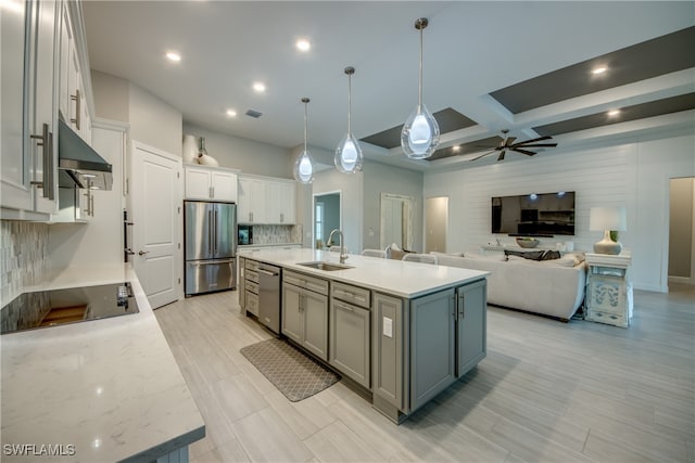 kitchen featuring sink, hanging light fixtures, stainless steel appliances, decorative backsplash, and a kitchen island with sink