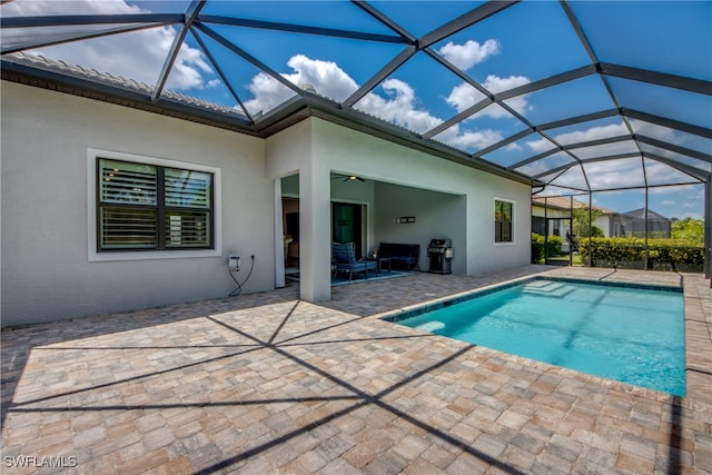 view of pool featuring a patio area, grilling area, and glass enclosure