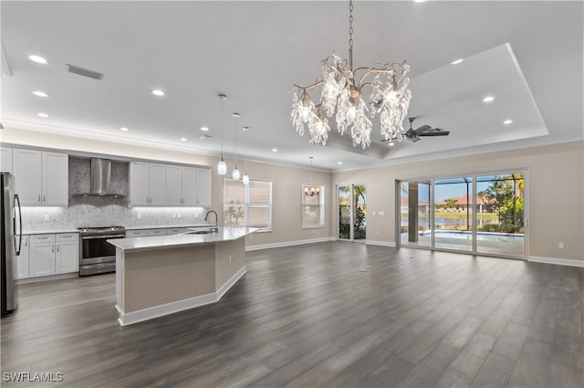 kitchen featuring appliances with stainless steel finishes, dark hardwood / wood-style flooring, wall chimney exhaust hood, pendant lighting, and an inviting chandelier