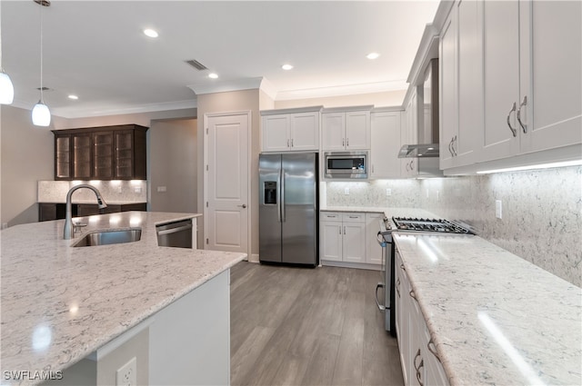 kitchen featuring sink, light stone counters, light hardwood / wood-style floors, decorative light fixtures, and appliances with stainless steel finishes