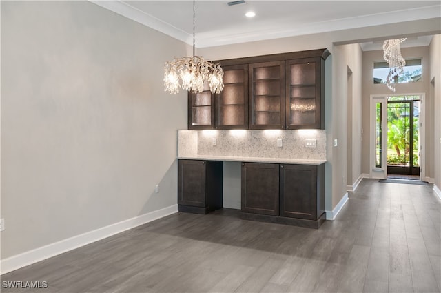 interior space with dark hardwood / wood-style floors, dark brown cabinetry, ornamental molding, and a chandelier