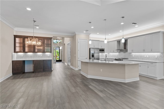 kitchen featuring a center island with sink, wall chimney exhaust hood, hardwood / wood-style floors, and appliances with stainless steel finishes