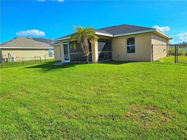 back of property with a sunroom and a lawn