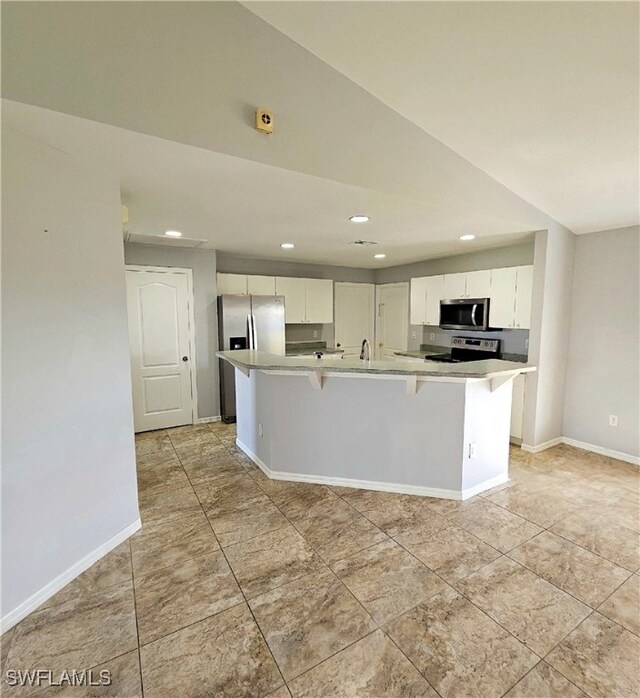 kitchen with white cabinetry, a kitchen bar, stainless steel appliances, and an island with sink