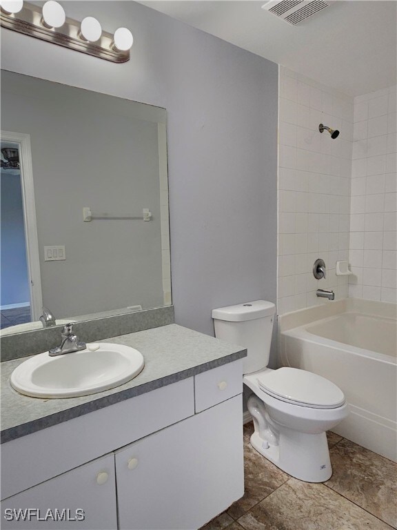 full bathroom featuring vanity, tiled shower / bath combo, toilet, and tile patterned floors