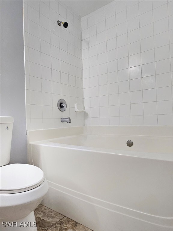 bathroom with tiled shower / bath, tile patterned floors, and toilet