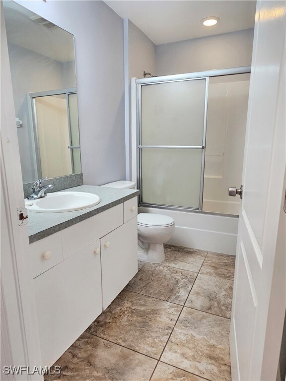 full bathroom featuring vanity, toilet, and bath / shower combo with glass door