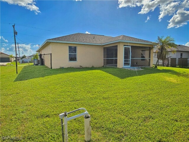 rear view of property featuring a yard and a sunroom