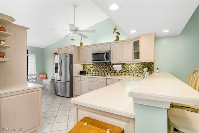 kitchen with kitchen peninsula, sink, lofted ceiling, and appliances with stainless steel finishes