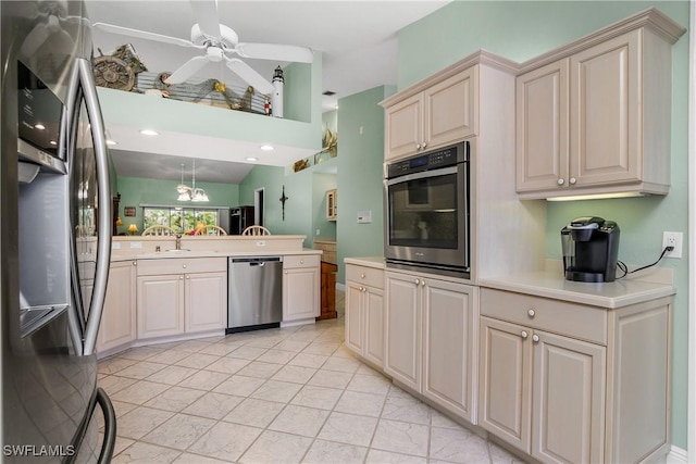 kitchen featuring stainless steel appliances, light countertops, ceiling fan, a sink, and a peninsula