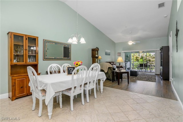 dining area with ceiling fan with notable chandelier, marble finish floor, high vaulted ceiling, and visible vents