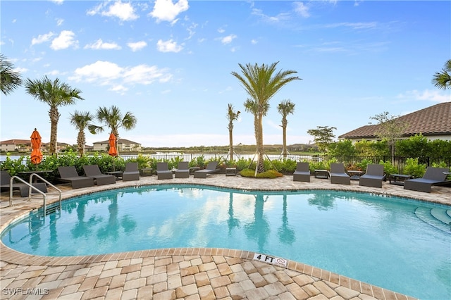 view of swimming pool with a patio and a water view