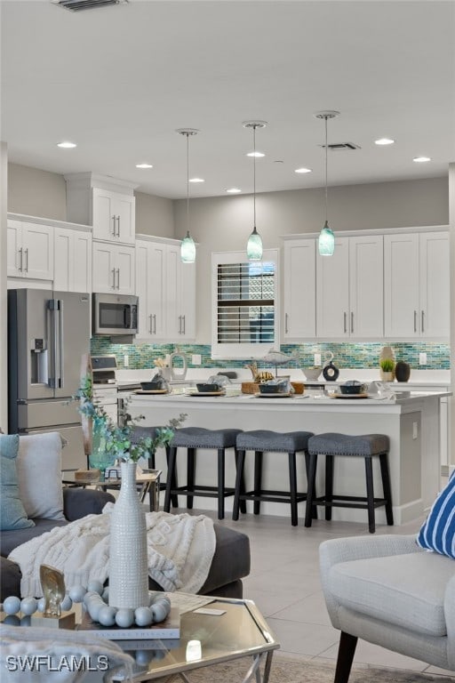 kitchen with white cabinetry, decorative light fixtures, a breakfast bar, and stainless steel appliances