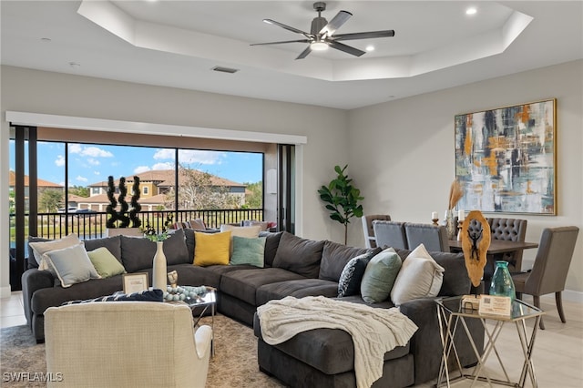 living room featuring ceiling fan and a raised ceiling