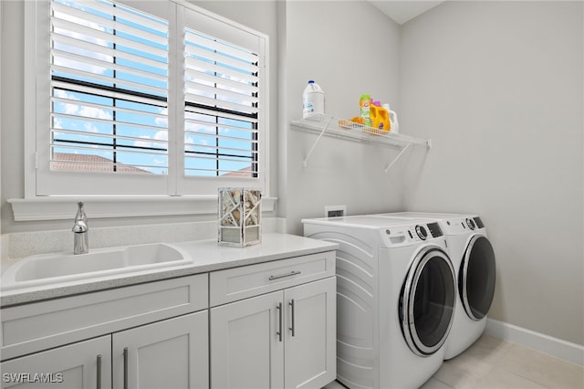 laundry area with cabinets, washer and clothes dryer, sink, and light tile patterned floors