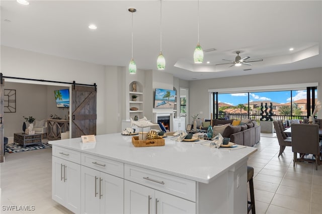 kitchen with pendant lighting, a tray ceiling, a barn door, and white cabinets