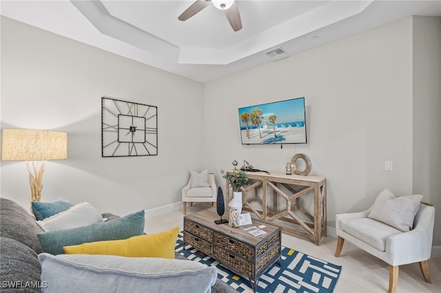 living room with a tray ceiling and ceiling fan