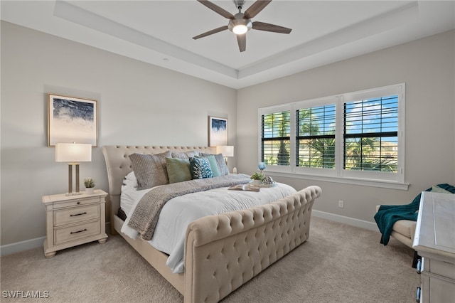 carpeted bedroom with ceiling fan and a raised ceiling