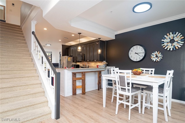 dining area with light hardwood / wood-style floors and ornamental molding