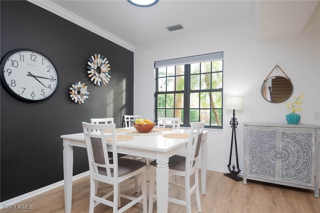 dining space featuring light hardwood / wood-style floors and crown molding